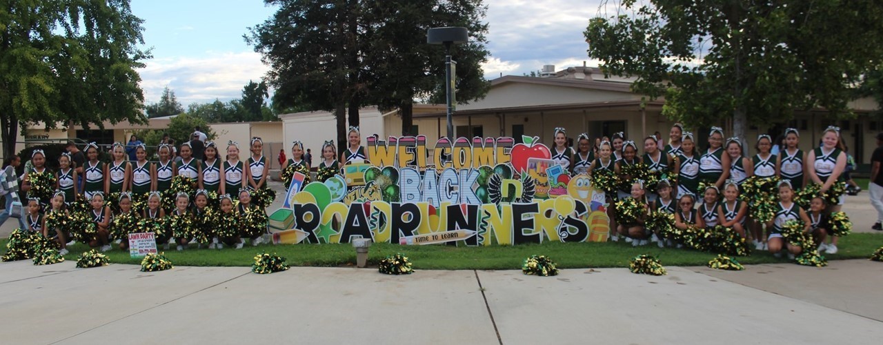 cheerleaders surrounding sign that says &#34;Welcome Back Roadrunners&#34;